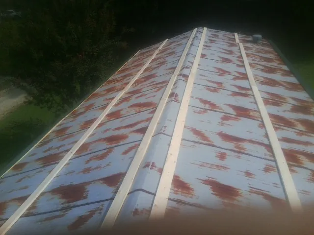 Rusted metal roof panels with new wood purlins before replacement — Storm Damage Roof Repair in Lansford by Roofing Brothers