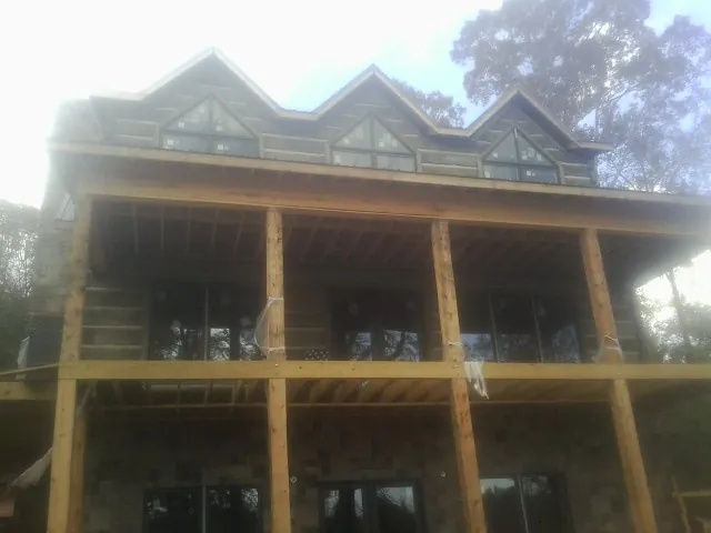 Dormers and porch framing on a large log home under construction — Roof Coating work by our crew in Lansford