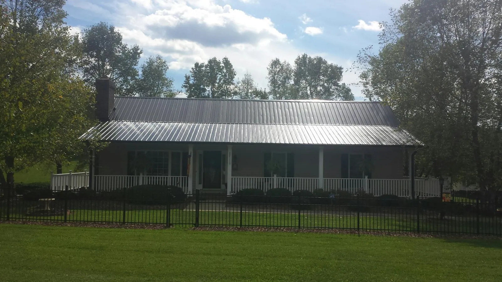 Gray metal roof on a brick ranch with a full width front porch — Gutter Guard Installation work by our crew in Lansford